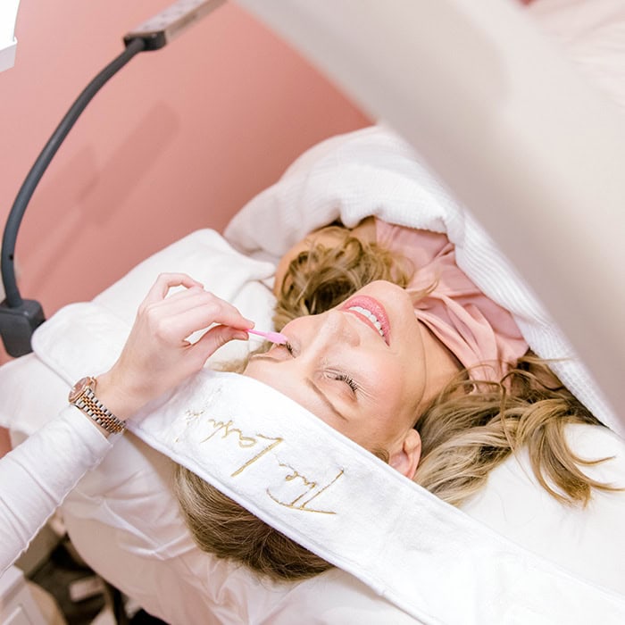 A guest relaxing during a lash appointment in a private suite